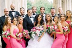 a group of people standing next to each other in front of some columns and flowers