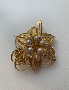 This listing is for the Midcentury Orchid Gold tone metal and faux pearl brooch that you see featured in photos. This pin is gold plated metal with assortment of white faux pearl accents. This pin/brooch is in nice used condition. Please take a look at photos, this is the actual brooch you will receive in the order. Please follow our shop link for more vintage! https://www.etsy.com/shop/CandilandArt Gold Flower Brooch Lapel Pin, Gold Flower Brooch For Formal Occasions, Elegant Gold Flower Lapel Pin, Gold Costume Jewelry Pins For Wedding, Elegant Gold Filigree Brooches, Gold Flower Brooch For Wedding, Elegant Gold Flower Brooch, Gold Flower Pins For Wedding, Elegant Gold Flower Brooches