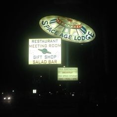 a neon sign that says space age lodge and is lit up in the dark at night