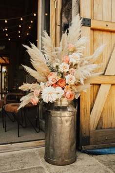 a vase filled with lots of flowers sitting on top of a stone floor next to a wooden door