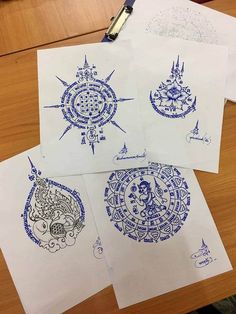 four different designs on paper sitting on top of a wooden table