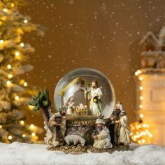 snow globe with nativity scene displayed in front of christmas tree