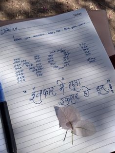 a notepad with writing on it and a leaf in the foreground, next to a pen