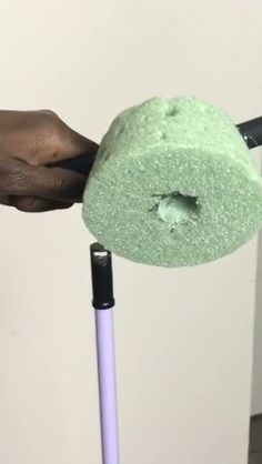 a person is cleaning the floor with a green mop and a blue handlebar