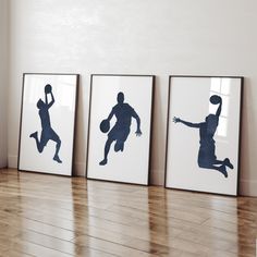 three framed photos of basketball players on the wall in a room with hard wood flooring