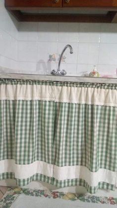 a kitchen sink with a green and white checkered curtain