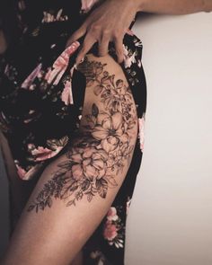 a woman's thigh with flowers on it and her leg showing the tattoo design