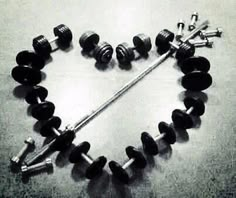 a heart made out of dumbbells on the floor with two sets of screws