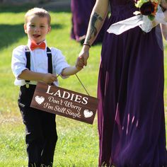 a young boy holding the hand of an older woman in a purple dress and red bow tie