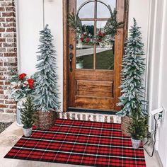 the front door is decorated for christmas with evergreen trees and plaid rugs on it