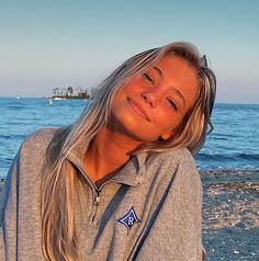 a woman sitting on top of a beach next to the ocean