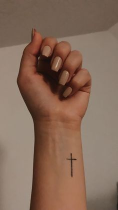 a woman's wrist with a cross tattoo on it