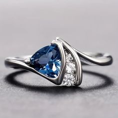 a blue and white diamond ring sitting on top of a gray surface with diamonds around it