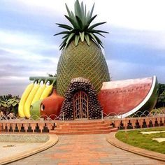 a giant pineapple and banana sculpture in the middle of a brick walkway next to a park