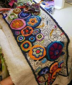 a woman is working on a piece of art with crochet and yarns