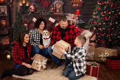 the family is sitting on the floor with their dog and presents in front of them