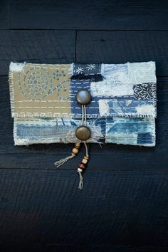 a blue and white patchwork purse with tassels hanging from it's side