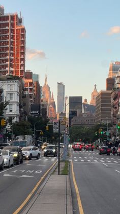 a city street filled with lots of traffic next to tall buildings and skyscrapers in the distance