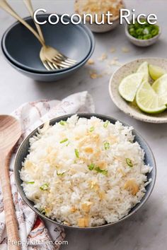 coconut rice in a bowl with spoons and lime slices on the side, along with other dishes