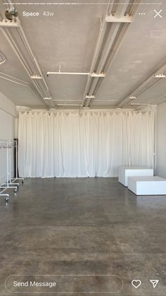 an empty room with white drapes on the walls