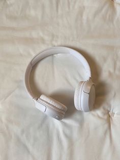 two white headphones sitting on top of a bed