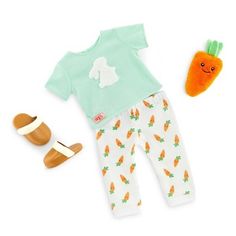 a baby doll with a carrot outfit and shoes next to a toy carrot on a white background