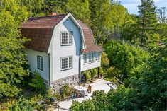 an aerial view of a white house surrounded by trees and greenery in the woods