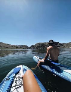 a man sitting on top of a blue surfboard in the ocean next to another person