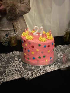 a pink birthday cake sitting on top of a table