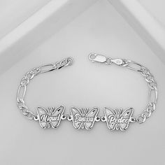 "STERLING SILVER BUTTERFLY FAMILY NAMES."  Metal: Solid 925 Sterling Silver.  Chain type Bracelet: Figaro Diamond Cut.   Clasp Link: Lobster Claw lock.  Thickness Chain: 4.8 mm.  Butterfly sizes each Name:18 mm Wide X 14 mm Hight.  This type of Family ID butterfly Bracelet its deep engrave names and figaro chain is makes great for everyday wear.  This Personalized style with custom charm makes a stunning statement Bracelet.  Can customize this jewelry with any family name of your choice and also determine the size of the bracelet in order to ensure that it is perfectly fitted on your wrist. Will be made with the same kind of typography that is shown in the image. This fine piece of jewelry is made with real Solid 925 Sterling Silver, (we do not use any coating or plated metal on our jewelr Silver Sterling Silver Butterfly Bracelet, Butterfly-shaped Sterling Silver Bracelet, Sterling Silver Butterfly Bracelets, Silver Butterfly Bracelet For Gift, Butterfly Shaped Silver Bracelet Gift, Silver Butterfly Bracelets For Gifts, Silver Sterling Silver Name Charm Bracelet, Engraved Sterling Silver Bracelet, Figaro Bracelet