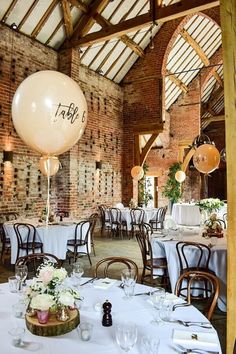 a room filled with lots of tables covered in white tablecloths and topped with balloons