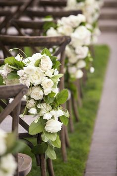 rows of wooden chairs with white flowers and greenery on the back one row is empty