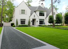 a large white house sitting on top of a lush green field next to a driveway