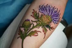 a thistle flower tattoo on the arm