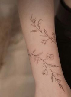 a woman's arm with flowers and leaves on it