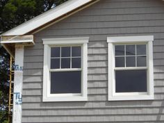 two windows on the side of a gray house