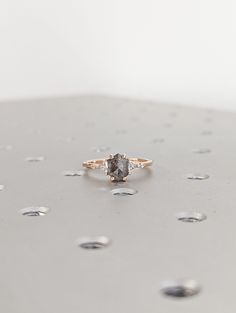 a diamond ring sitting on top of a silver surface with drops of water around it