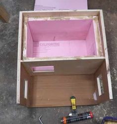 an open box sitting on top of a floor next to some screws and other tools