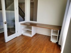 an empty room with wooden flooring and white shelves on either side of the door