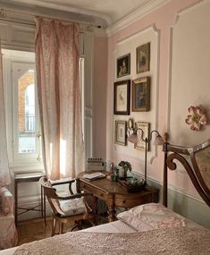 an old fashioned bedroom with pink walls and antique furniture, including a desk in the corner