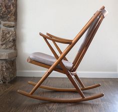 a rocking chair sitting on top of a hard wood floor next to a brick wall