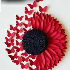 a large red flower surrounded by lots of butterflies on a white surface with black center