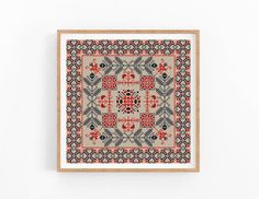 an embroidered square on a white wall with red and blue designs in the center,