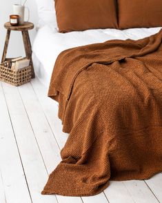 a bed with brown blankets and pillows on top of it next to a night stand