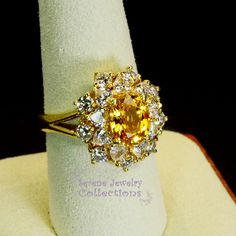 Thank you for coming in! This Vintage Ring has a strong striking yellow sapphire as its center piece. The sapphire is bezel set into a fancy setting with 8 heart and 8 round diamonds totaling 1.8 carats! Ring Size: 7.75 Total Weight: 9.58 grams Precious Metal: 18k solid gold Precious stones: -Yellow Sapphire: 2.92 carats, 9mm x 7.3mm -White Round Diamonds: 1.8 ct Hallmark: A18K Luxury Yellow Multi-stone Jewelry, Yellow Multi-stone Sapphire Ring, Yellow Brilliant Cut Ring, Fine Yellow Oval Sapphire Ring, Yellow Oval Sapphire Diamond Ring, Oval Yellow Sapphire Ring With Diamonds, Oval Yellow Sapphire Ring With Center Stone, Anniversary Jewelry With 17 Jewels And Citrine, Dazzling Yellow Jewelry With Halo Setting