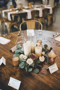 a table with candles, flowers and place cards on it for guests to sit at