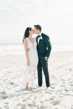 a bride and groom kissing on the beach