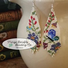 a pair of beaded bird earrings sitting on top of a table next to books