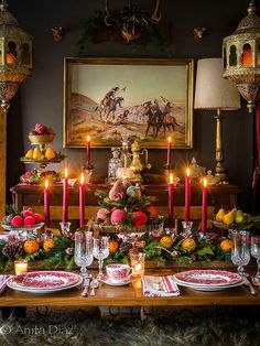 a dining room table set for christmas dinner with candles and fruit on the plates in front of it