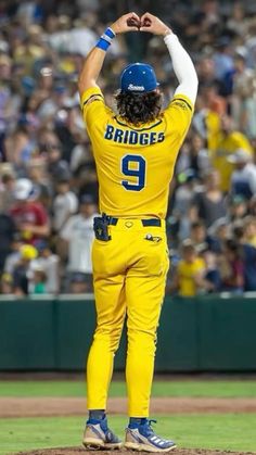 a baseball player is standing on the mound with his hands in the air and arms raised